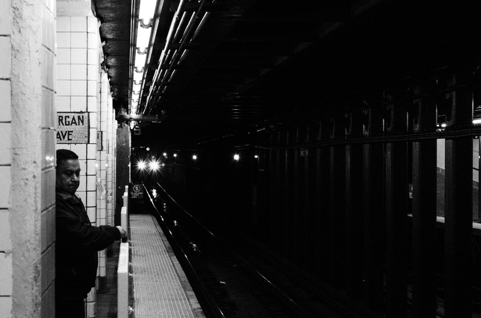 The train approaches as a man waits at Morgan Street Station
